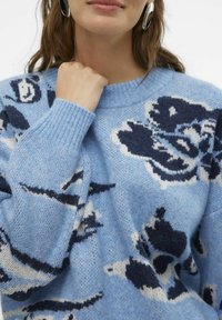 Svetr z vlněné směsi modré barvy s květinovým vzorem v námořnické a krémové barvě, kulatým výstřihem a žebrovanými manžetami pro texturu.