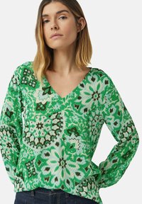 Grüner, gemusterter V-Ausschnitt-Pullover mit floralen und geometrischen Designs in verschiedenen Grüntönen, Türkis und Braun, mit langen Ärmeln.