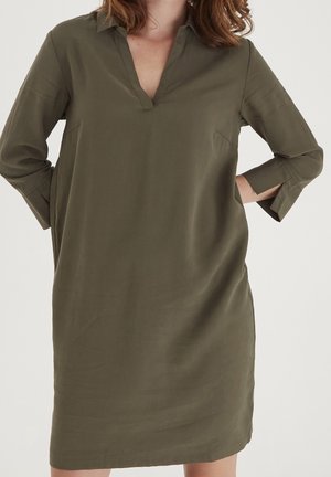 Robe olive verte, longueur genoux avec un décolleté en V et un col. Présente des manches trois-quarts avec des fentes, fabriquée dans un tissu lisse et léger.