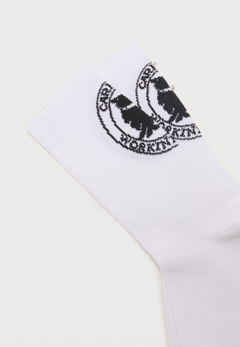 Two folded white socks with a black circular logo featuring a bear and text around the edge on the cuff.