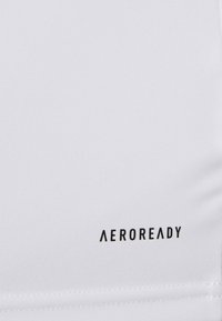 Bijela atletska tkanina s crnim logotipom "AEROREADY". Tekstura je glatka s suptilnim rastezljivim svojstvom. Šavovi su vidljivi duž rubova.