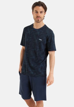 T-shirt bleu marine à manches courtes avec un motif de feuilles, col rond et détail de logo. Associé à un short bleu marine uni. Tissu doux et coupe décontractée.