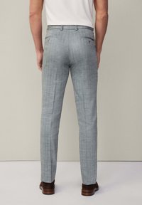 Lichtgrijze linnen broek met een textuurafwerking, voorzien van twee achterzakken met knopen en een rechte pijp, gecombineerd met donkerbruine schoenen.