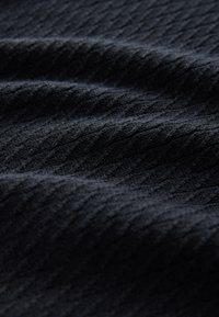 Zwart gebreide stof met een gestructureerd, geribbeld patroon, met subtiele variaties in diepte en een zachte, ondoorzichtige uitstraling.