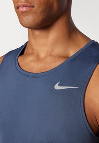 Marineblå atletisk tanktop med struktureret stof og et lille sølvfarvet Nike-logo på venstre bryst.