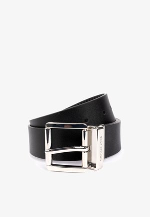 Ceinture en cuir noir avec boucle rectangulaire en argent gravée de "MICHAEL KORS", enroulée avec des trous de réglage visibles sur un fond blanc.