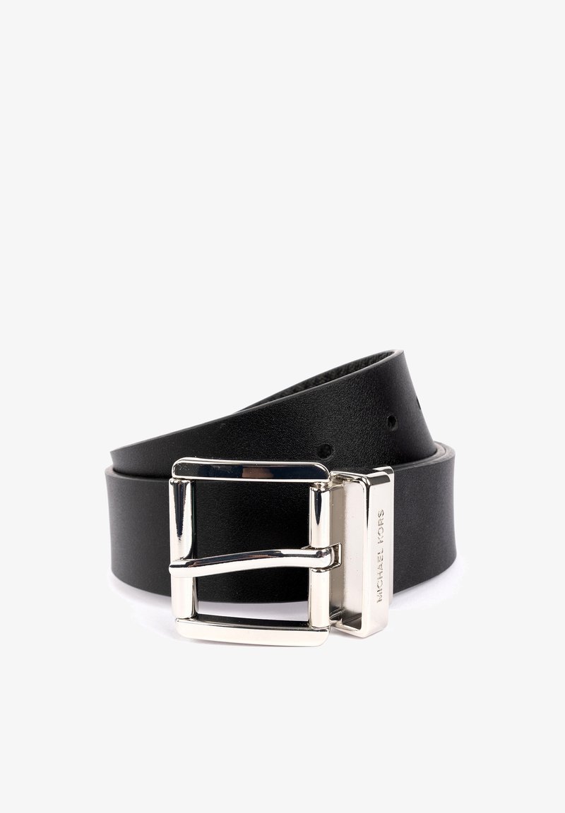 Ceinture en cuir noir avec boucle rectangulaire en argent gravée de "MICHAEL KORS", enroulée avec des trous de réglage visibles sur un fond blanc.