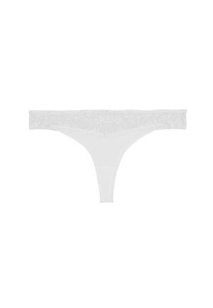 String tanga en dentelle blanche avec détails de broderie florale le long de la ceinture, présenté sur un fond blanc uni.