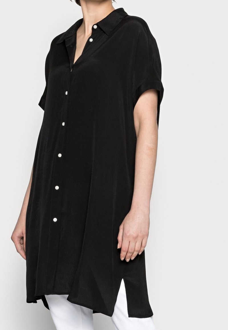 Abito camicia nero a maniche corte con chiusura a bottoni frontale. Presenta un colletto, una linea dritta e spacchi laterali, realizzato in un tessuto liscio.