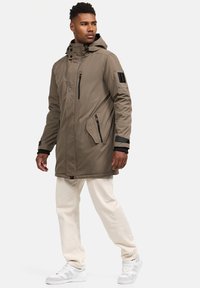 Khaki parka jaka ar kapuci, sānu kabatām un melnā krāsā iestrādātām detaļām. Izgatavota no gludas auduma, ar rāvējslēdzējiem un ribotām piedurknēm.