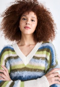 V-neck sweater featuring fuzzy, striped patterns in shades of blue, green, cream, and brown. Soft, textured fabric with long sleeves.