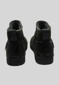 Stivaletti alla caviglia in suede nero con rivestimento interno morbido e linguetta posteriore testurizzata. Forma semplice e arrotondata con suola piatta.