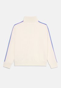 Felpa color crema con colletto alto e maniche lunghe. Presenta dettagli a strisce blu e viola lungo le spalle e le maniche.