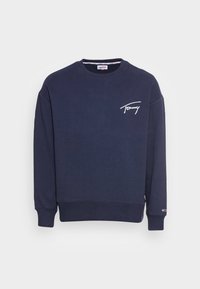 Marinblå tröja med rund hals, långa ärmar, "Tommy"-logotyp i vit kursiv stil på bröstet och liten Tommy Hilfiger-flagga på vänster mudd.