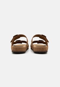 Sandalias de suede marrón con dos correas ajustables, una plantilla contorneada y una suela de goma texturizada, vistas desde atrás.
