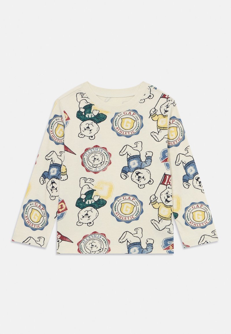 Hosszú ujjú krémszínű ing, amely színes mesebeli mackó grafikákkal és különböző színű, kör alakú GAP márkajelekkel díszített.