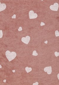 Pink textured fabric with scattered white heart shapes, varying in size, featuring a soft, plush quality.