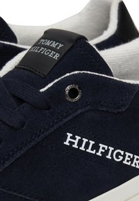 Zapatillas de ante azul marino con detalles en cuero negro y logotipo blanco. Presenta cordones y una superficie texturizada cerca de la suela.