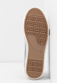 Suola di sneaker in gomma grigia con battistrada marrone testurizzato a motivi geometrici, accenti bianchi sui lati e un marchio di misura "37."