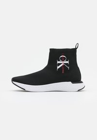 Czarny sneaker za kostkę z dzianinową cholewką, białą wzorzystą podeszwą oraz logo Calvin Klein Jeans w bieli i czerwieni po boku.