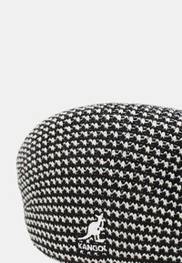 Cappello in fantasia pied de poule bianco e nero realizzato in tessuto strutturato, con un grande logo bianco Kangol sul lato.
