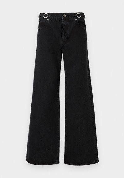 Fekete, széles szárú farmernadrág, magas derékkal, nagy elülső zsebekkel és ezüst színű, kör alakú fém díszítéssel a derékrészen.