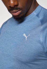 Blå athletic t-skjorte laget av strukturert stoff har rund hals og en liten hvit Puma-logo på brystet.