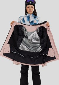 Skijakke med sort og lyserød ydre, der har en sølv isoleret foring, flere lommer og justerbar bund. Lynlås og trykknaplukninger.