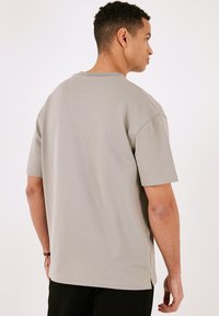 Grå bomulds t-shirt med korte ærmer, rund hals og lige pasform. Har sideslids i kanten og en glat, blød tekstur.
