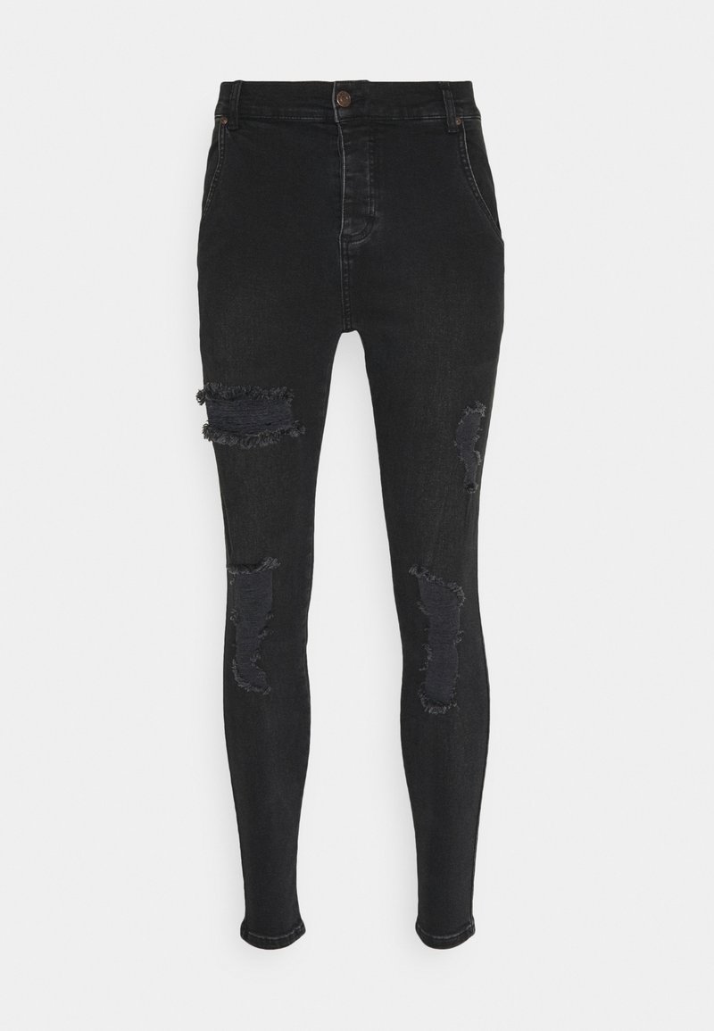 Pantalones skinny de denim negro de talle alto con desgastes y roturas en los muslos. Cuenta con dos bolsillos frontales y un cierre de botón.