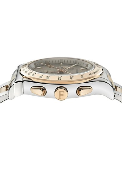 Vista lateral de un reloj cronógrafo plateado y dorado con dos botones pulsadores y una corona marcada con la letra "F" en una pulsera de metal.