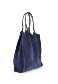 Marineblå suedetote med to brune læderhåndtag. Har en blød, struktureret overflade og et rummeligt, åbent design for nem adgang.