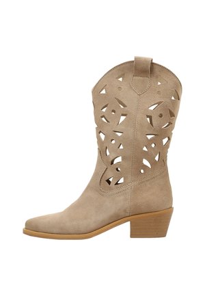 Bota de ante beige hasta media pantorrilla con patrones florales recortados y un tacón bloque de madera apilado.