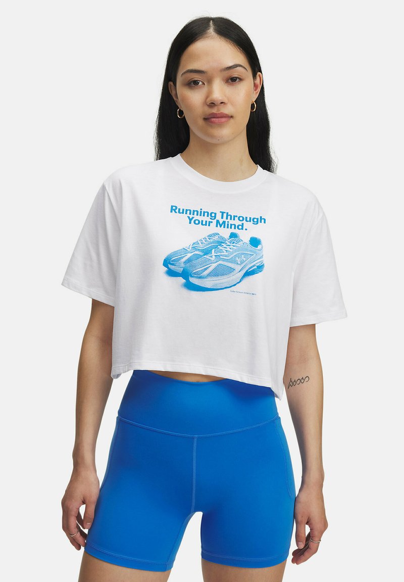White cropped t-shirt with blue graphic print of shoes and text. Blue high-waisted shorts. Circular earrings visible.