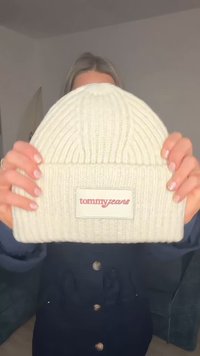 Biała dziergana czapka z prążkowaną fakturą. Posiada naszywkę z logo "tommyjeans" na czerwono na prostokątnym białym tle.