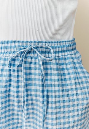 Modrá a bílá kostkovaná látka s elastickým pasem a lehkým, texturovaným materiálem. Design je ležérní a volný.
