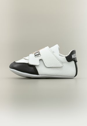 Scarpetta bianca e nera per bambino con cinturino in Velcro e grafica a cartone animato sulla parte superiore, vista di lato su uno sfondo neutro.