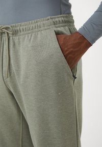Gray Nike sweatpants with a drawstring waist, soft texture, side pocket, and small logo detail on the leg.