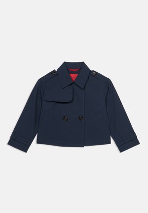 Tengerészkék, rövidített, dupla soros kabát széles gallérral, begombolható vállpántokkal, első zsebekkel és állítható ujjpántokkal.