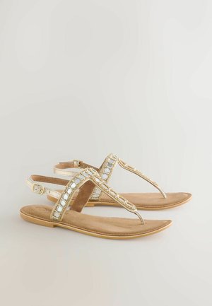 Plat gevlochten sandalen met tan suède, voorzien van gouden accenten, een teenslipperontwerp en een verstelbare enkelriem.