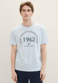 Svetlo modra bombažna majica z okroglim izrezom, kratkimi rokavi in sprednjim tiskom z napisom „Tom Tailor Essentials 1962“ v debeli pisavi.