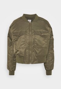 Veste bomber vert olive avec fermeture éclair à l'avant, deux poches poitrine, poignets côtelés et silhouette courte. Finition satinée et détails de couture plates.