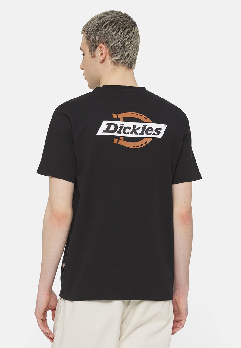 Camiseta de manga corta negra con un logo blanco y naranja en la parte de atrás. Hecha de algodón, con un corte relajado y un diseño de cuello redondo.