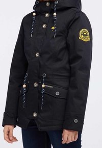 Czarna wodoodporna kurtka z kapturem, wyposażona w niebiesko-białe sznurki, zapięcia na guziki oraz boczne kieszenie z ozdobnymi akcentami.