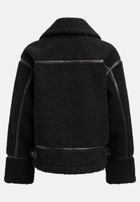 Schwarze Schafslederjacke mit einem Kunstlederbesatz, breitem Kragen und strukturierten Nähten. Zwei seitliche Schnallen am Saum sorgen für Detail.