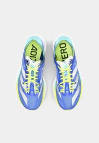 Baskets de course légères avec un dessus en textile bleu, des lacets jaunes et une semelle intermédiaire blanche avec une surface texturée. Marquage audacieux sur les semelles intérieures.