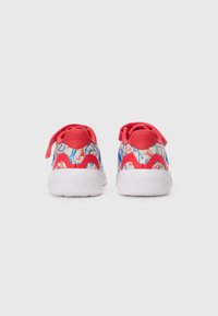 Baskets pour enfants avec semelles blanches, accents rouges et un motif abstrait bleu et rouge, présentées de l'arrière sur fond blanc.
