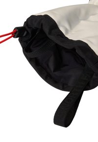 Dragsäck med en krämfärgad utsida, svart kant och inre foder. Har en röd snodd och svart bärrem, tillverkad av slitstarkt tyg.