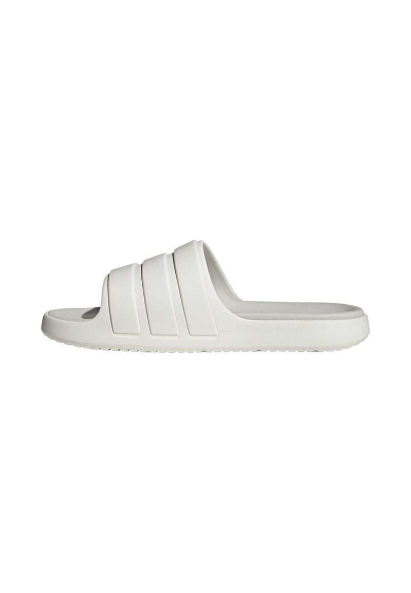Sandalia blanca tipo slip-on hecha de goma suave, con tres franjas horizontales prominentes en la parte superior, que presenta una suela plana y una plantilla texturizada.