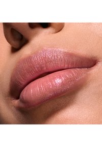 Glänzende, weiche, rosa Lippen mit leichtem Schimmer, die subtile Textur und Fülle im Kontrast zur glatten Haut zeigen. Nahaufnahme ohne umgebende Details.